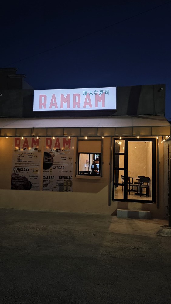 Fachada de Ram Ram de noche, con el letrero iluminado